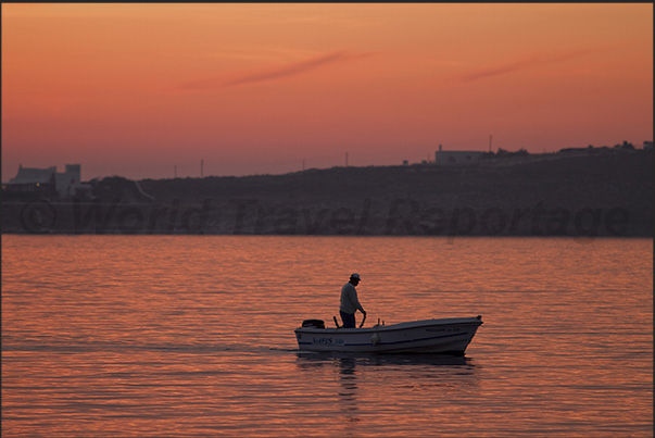 At sunset the small fishermen return to port while the large fishing boats go out for night fishing.