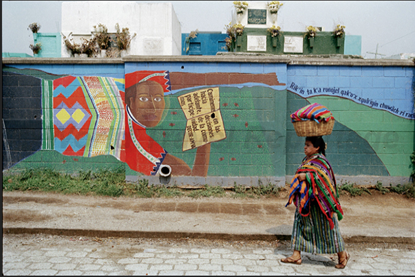 A woman in traditional clothes. Stand out the bright colors of the taperraj typical striped cloth used to cover the baskets